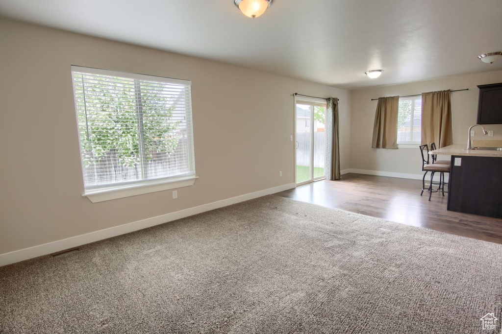Unfurnished living room with baseboards, light carpet, and a sink
