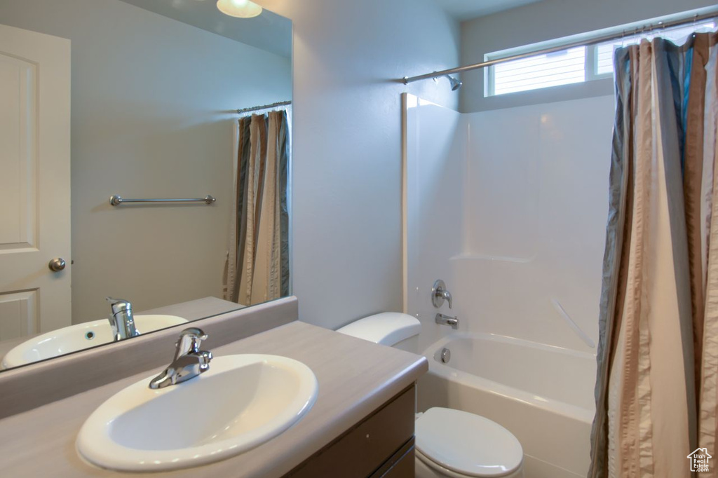 Bathroom featuring vanity, shower / bath combo, and toilet