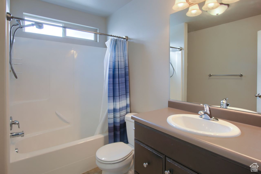 Bathroom with shower / bath combo with shower curtain, toilet, an inviting chandelier, and vanity
