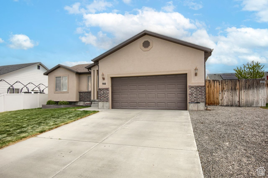 Ranch-style house featuring an attached garage, stucco siding, brick siding, and fence