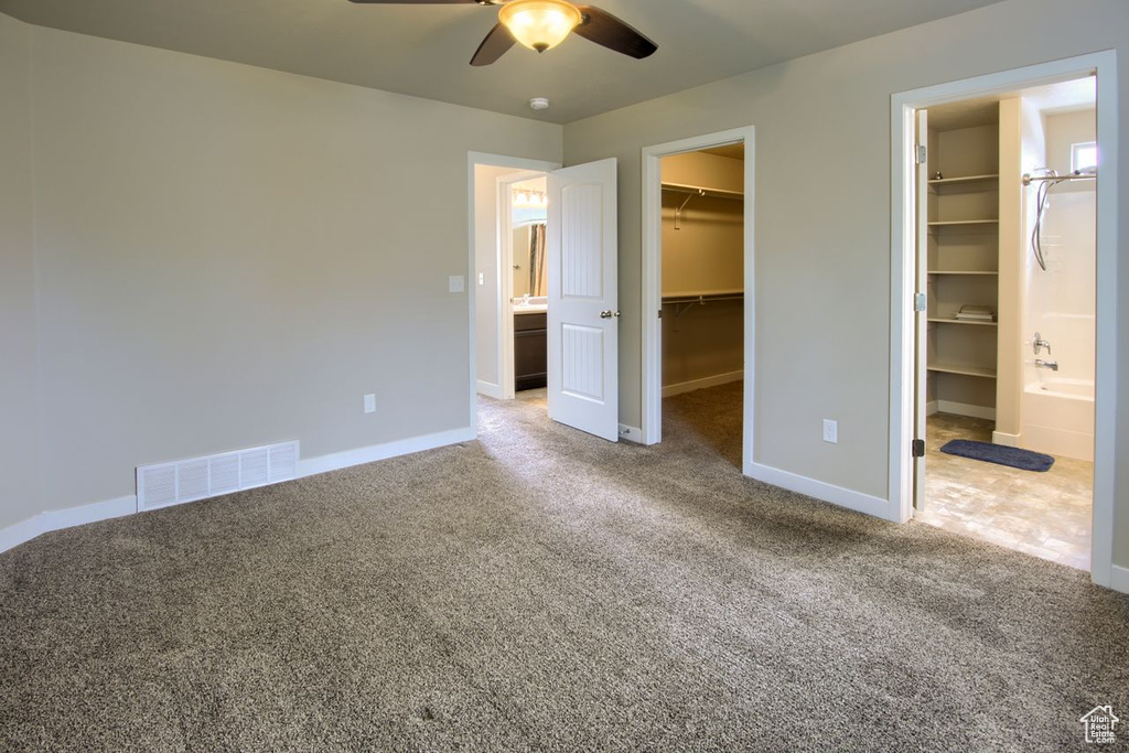 Unfurnished bedroom featuring a spacious closet, baseboards, carpet floors, and visible vents