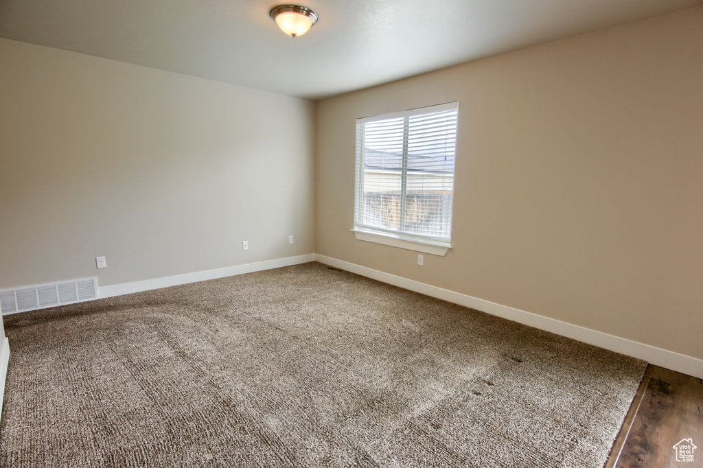 Carpeted spare room featuring baseboards and visible vents