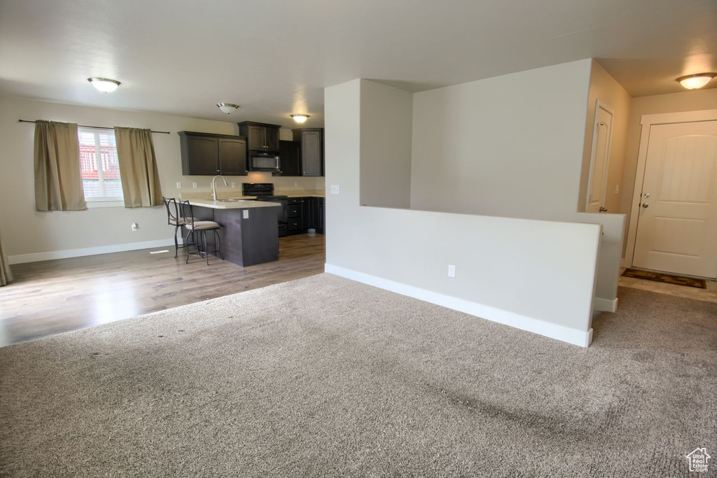 Living area with baseboards, light carpet, and light wood-style floors