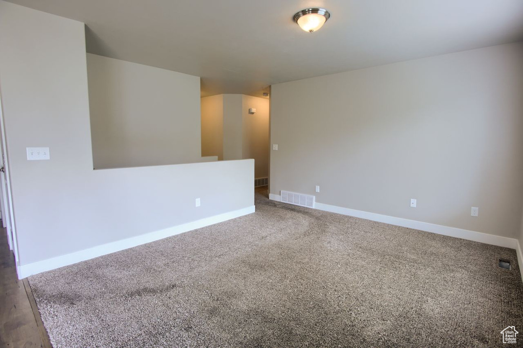Empty room featuring visible vents, carpet, and baseboards