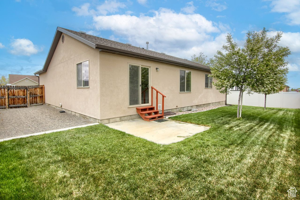 Rear view of property featuring entry steps, a fenced backyard, a patio area, and stucco siding