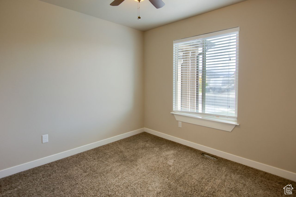 Spare room featuring carpet flooring, ceiling fan, baseboards, and a healthy amount of sunlight