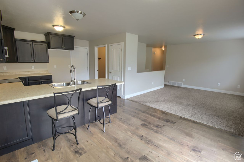 Kitchen featuring visible vents, a peninsula, baseboards, light countertops, and a sink