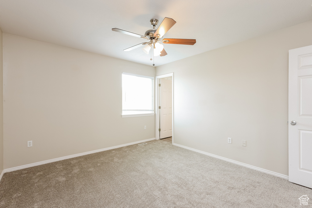 Empty room featuring a ceiling fan, light carpet, and baseboards