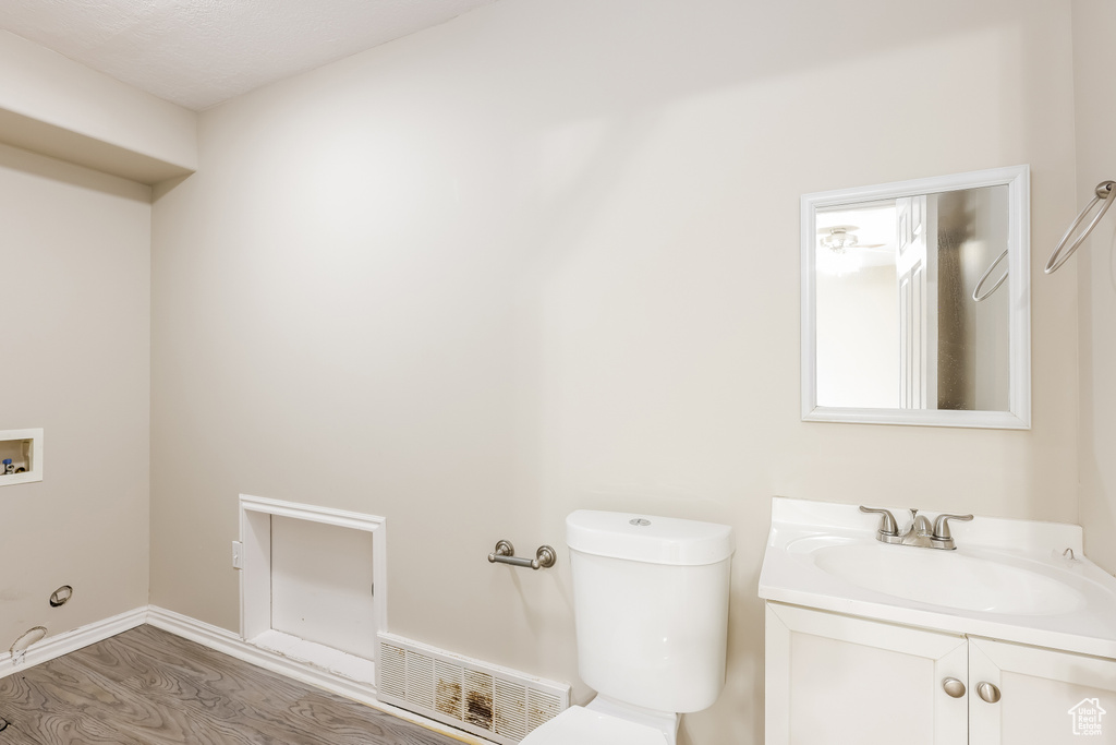 Bathroom with toilet, wood finished floors, visible vents, and vanity