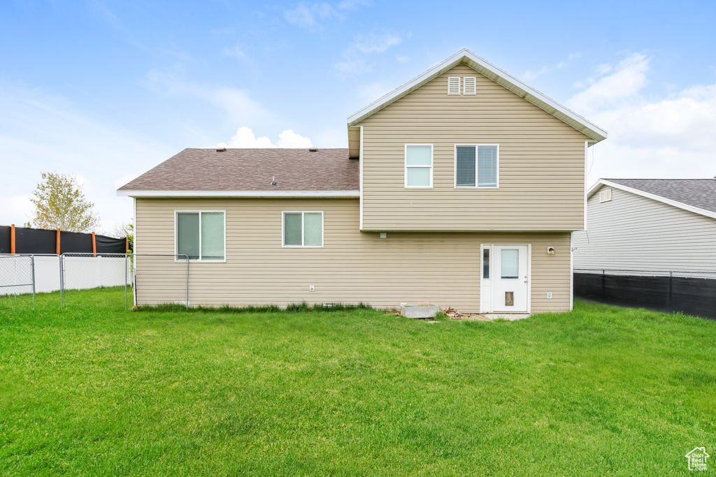 Rear view of house with a lawn, a fenced backyard, and roof with shingles