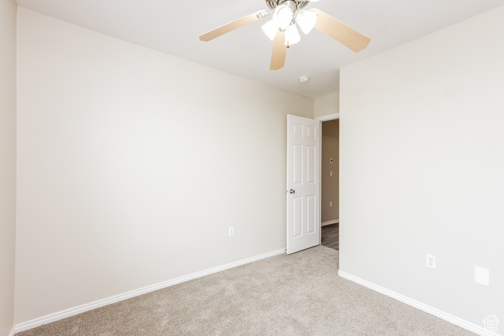 Spare room featuring light colored carpet, ceiling fan, and baseboards