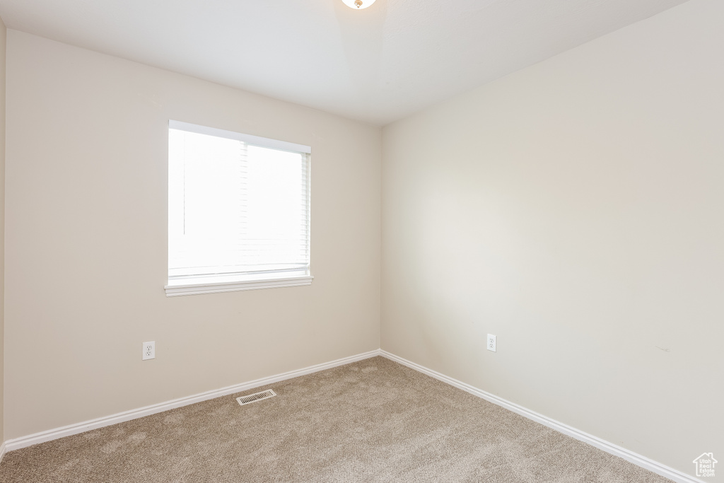 Carpeted empty room with baseboards and visible vents
