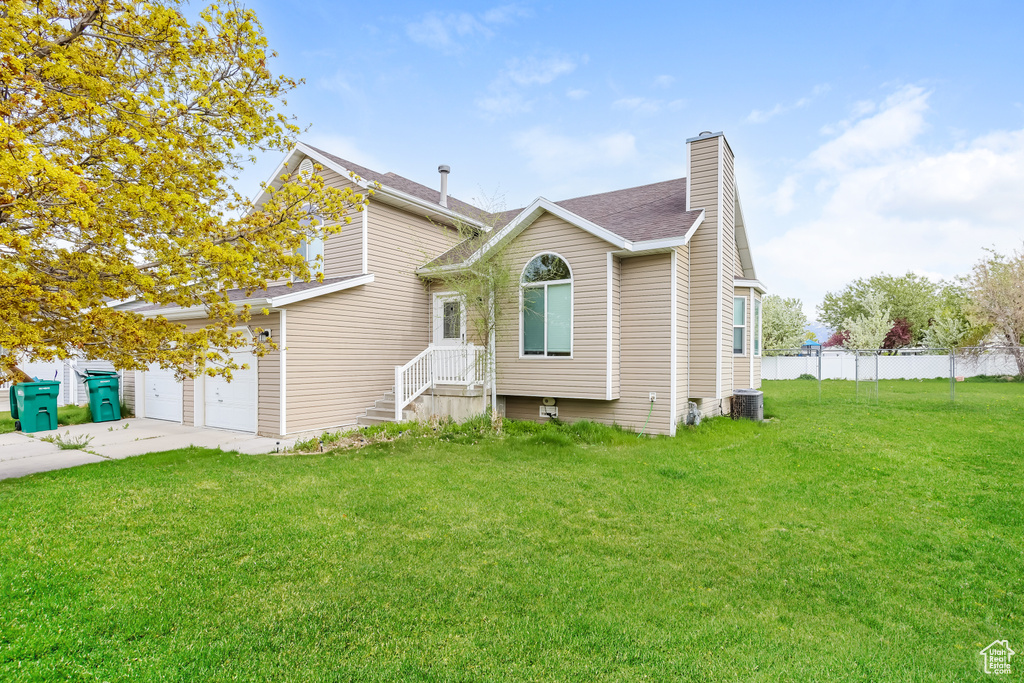View of front of property featuring fence, a chimney, cooling unit, and a front lawn