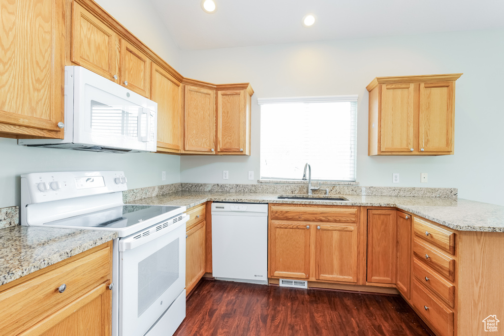 Kitchen featuring recessed lighting, white appliances, light stone counters, a sink, and dark wood-type flooring