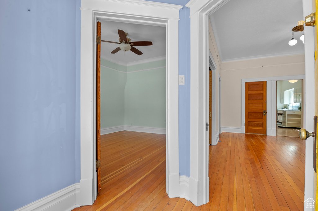 Hall with crown molding, light wood finished floors, and baseboards