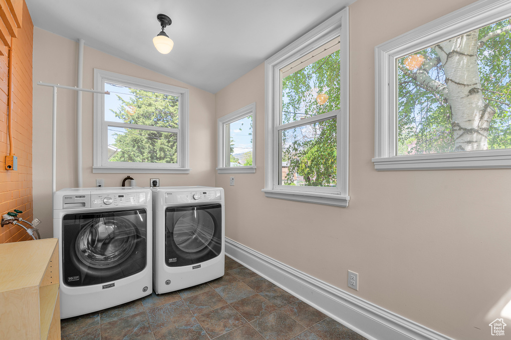 Laundry area with laundry area, stone finish floor, washing machine and dryer, and baseboards