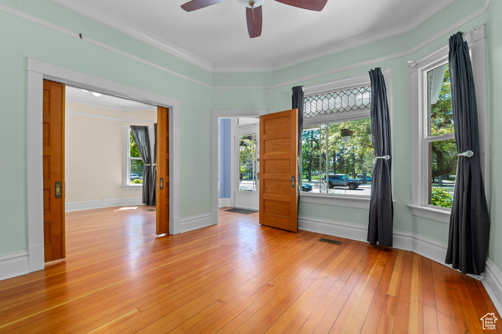 Spare room with light wood-style floors, visible vents, a ceiling fan, and a healthy amount of sunlight