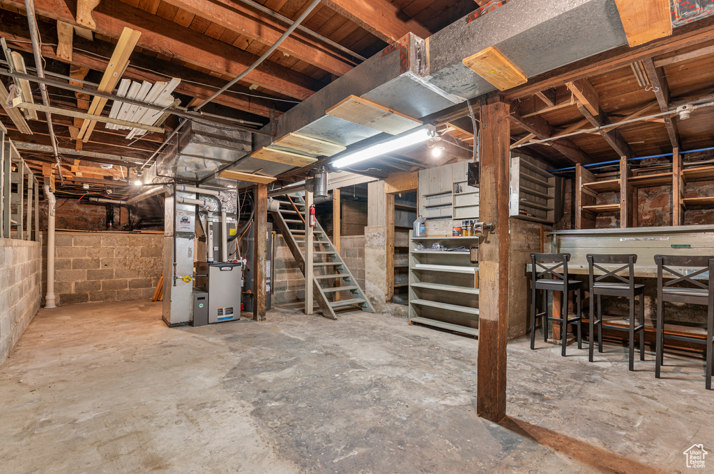 Unfinished basement featuring heating unit and stairway