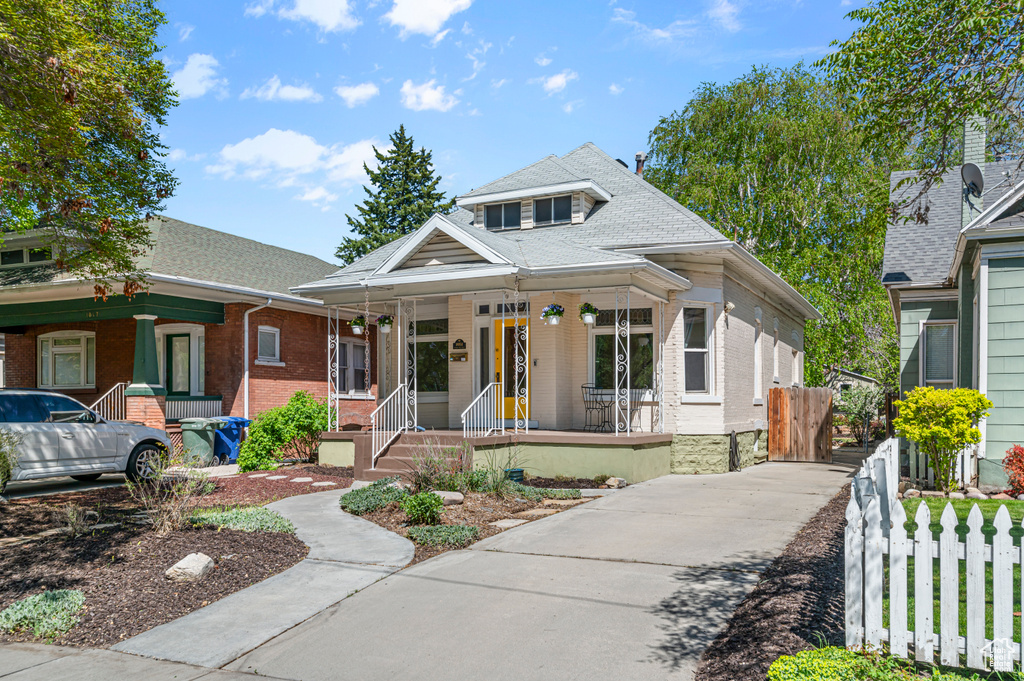 Bungalow featuring fence, concrete driveway, a porch, and brick siding