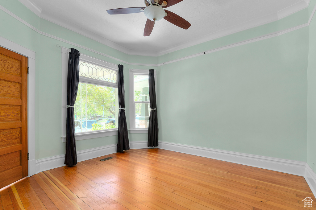 Unfurnished room featuring crown molding, ceiling fan, visible vents, and light wood-style floors