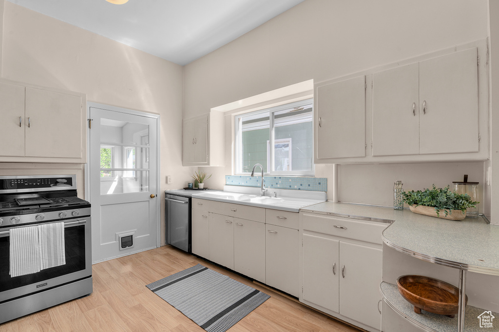 Kitchen featuring light countertops, stainless steel appliances, a sink, and light wood finished floors