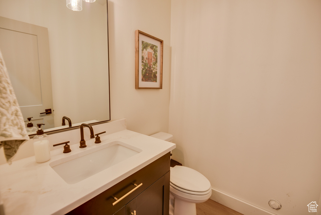 Bathroom with toilet, baseboards, wood finished floors, and vanity