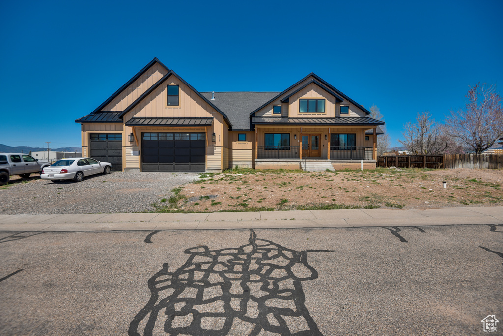 View of front of property with a porch, board and batten siding, a standing seam roof, metal roof, and gravel driveway