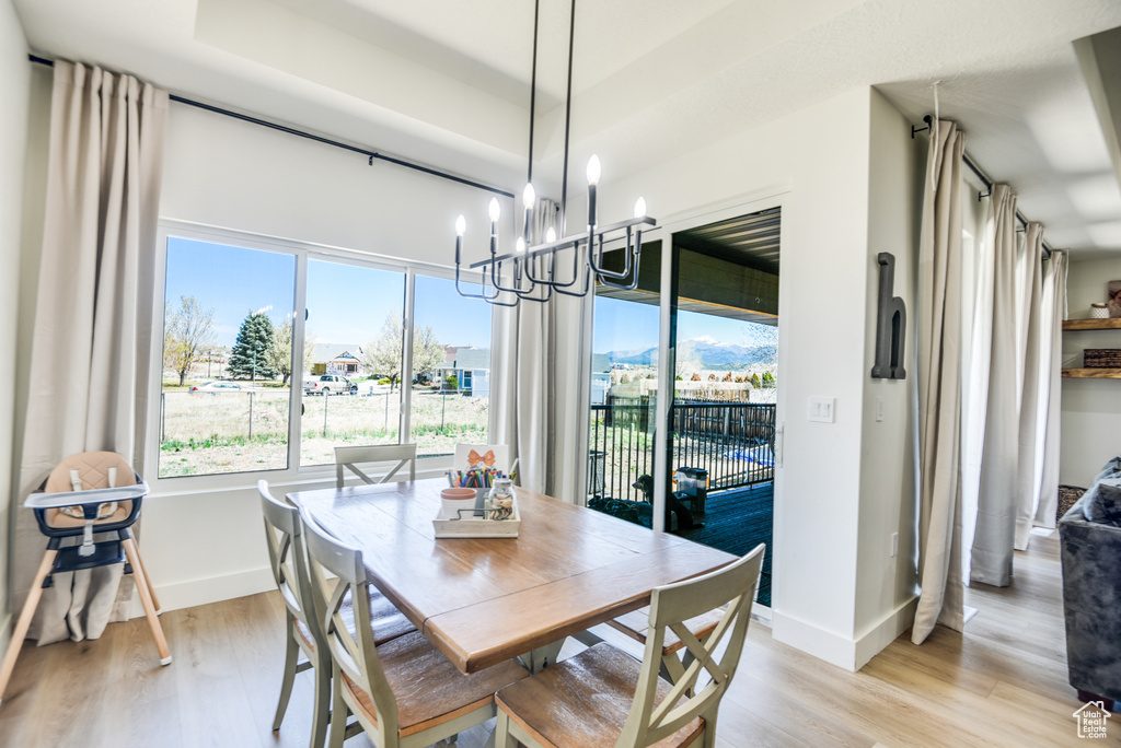Dining space featuring light wood-type flooring, baseboards, and an inviting chandelier