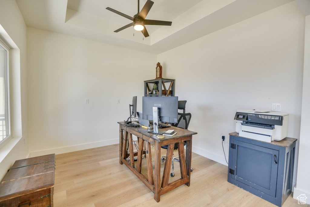Office featuring baseboards, a raised ceiling, light wood finished floors, and ceiling fan