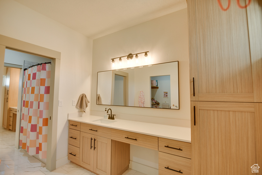 Full bath with vanity, marble finish floor, and curtained shower