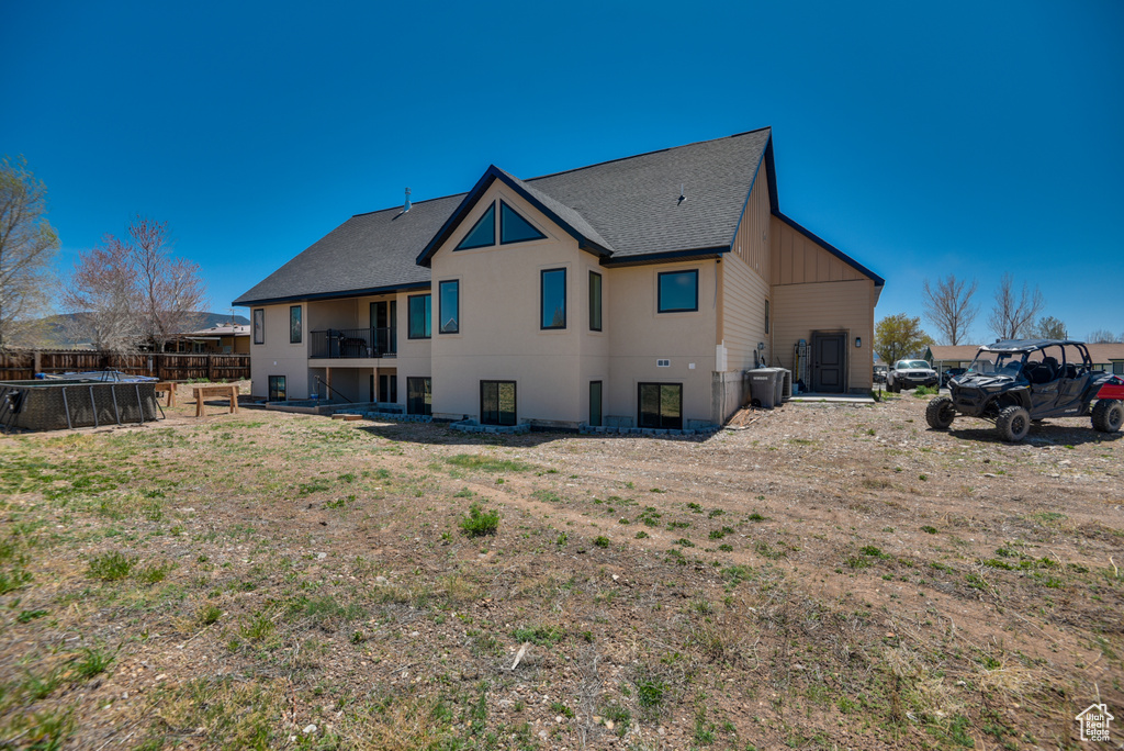 Back of property with roof with shingles, fence, and a balcony