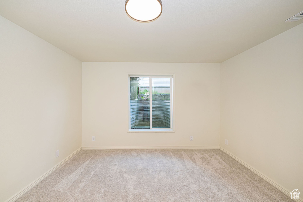 Empty room with baseboards, light carpet, and visible vents