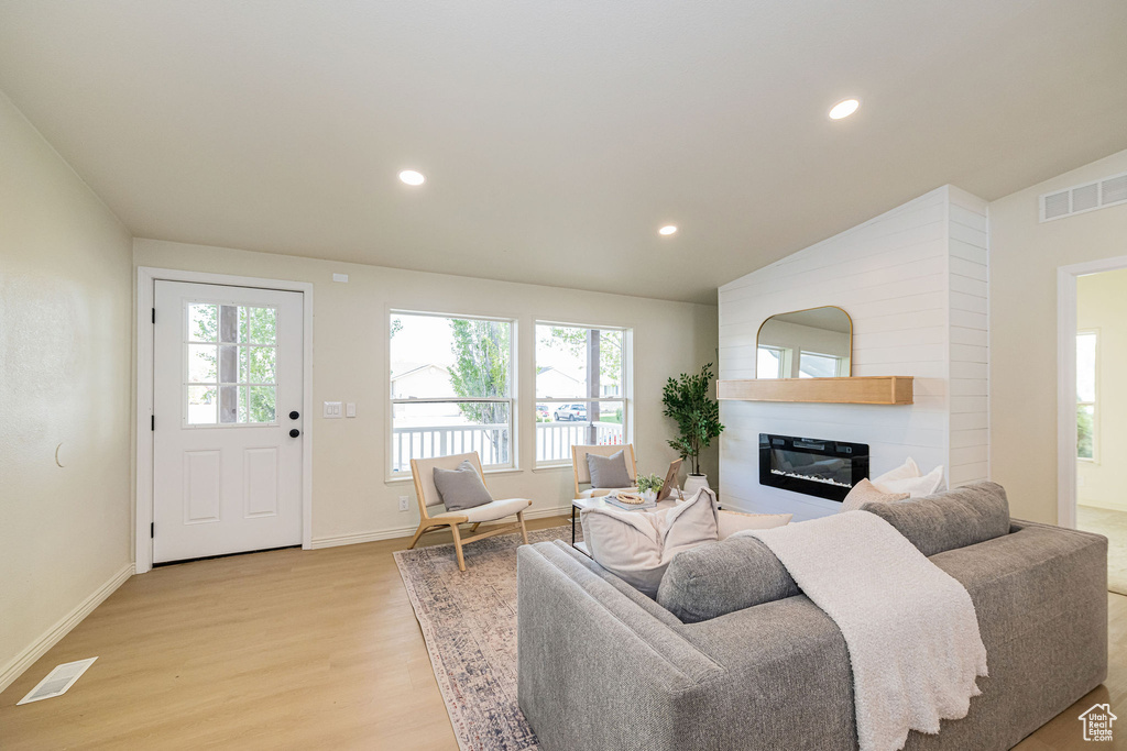 Living room with a fireplace, recessed lighting, light wood-style flooring, and visible vents
