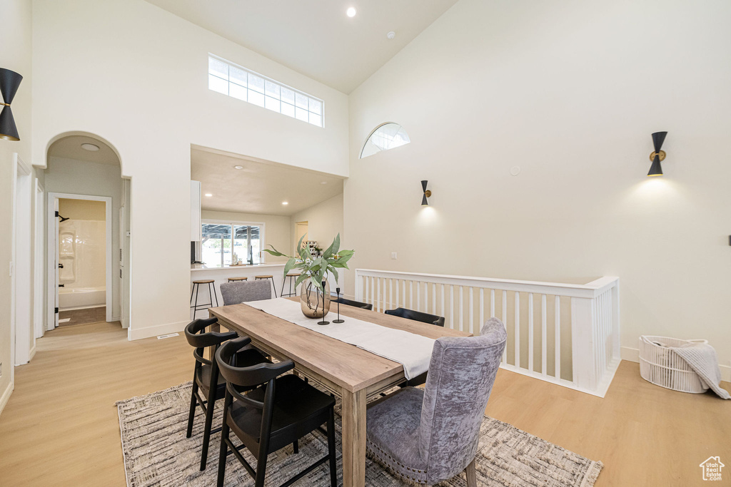 Dining area featuring recessed lighting, a high ceiling, baseboards, and light wood-style floors