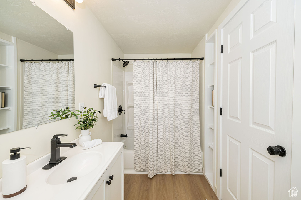 Full bath featuring shower / bath combo with shower curtain, wood finished floors, and vanity