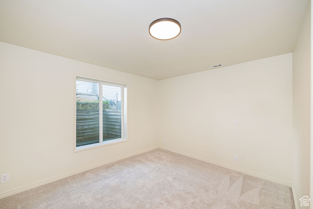 Empty room featuring carpet floors, baseboards, and visible vents