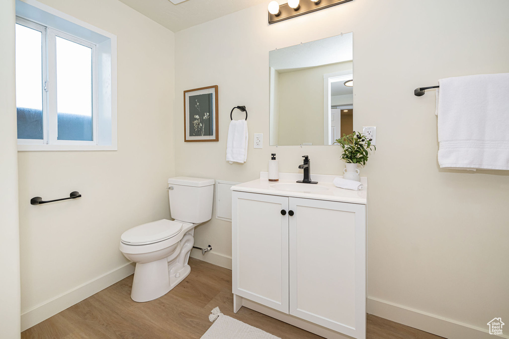 Bathroom featuring baseboards, wood finished floors, toilet, and vanity