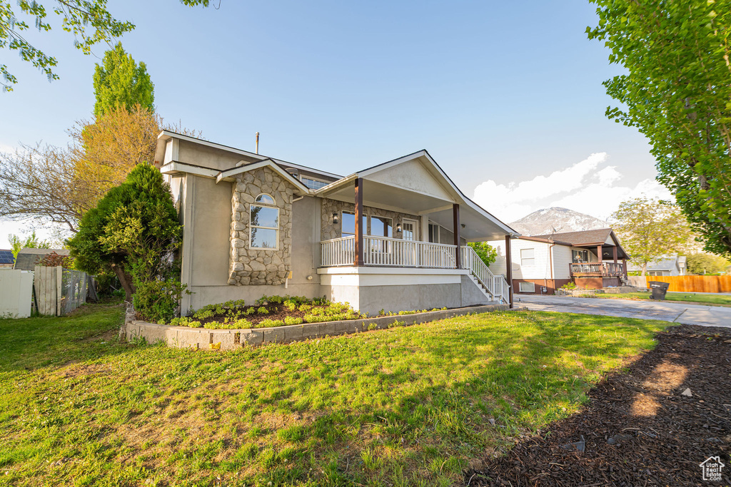 Ranch-style house with fence, stucco siding, a porch, a front yard, and driveway