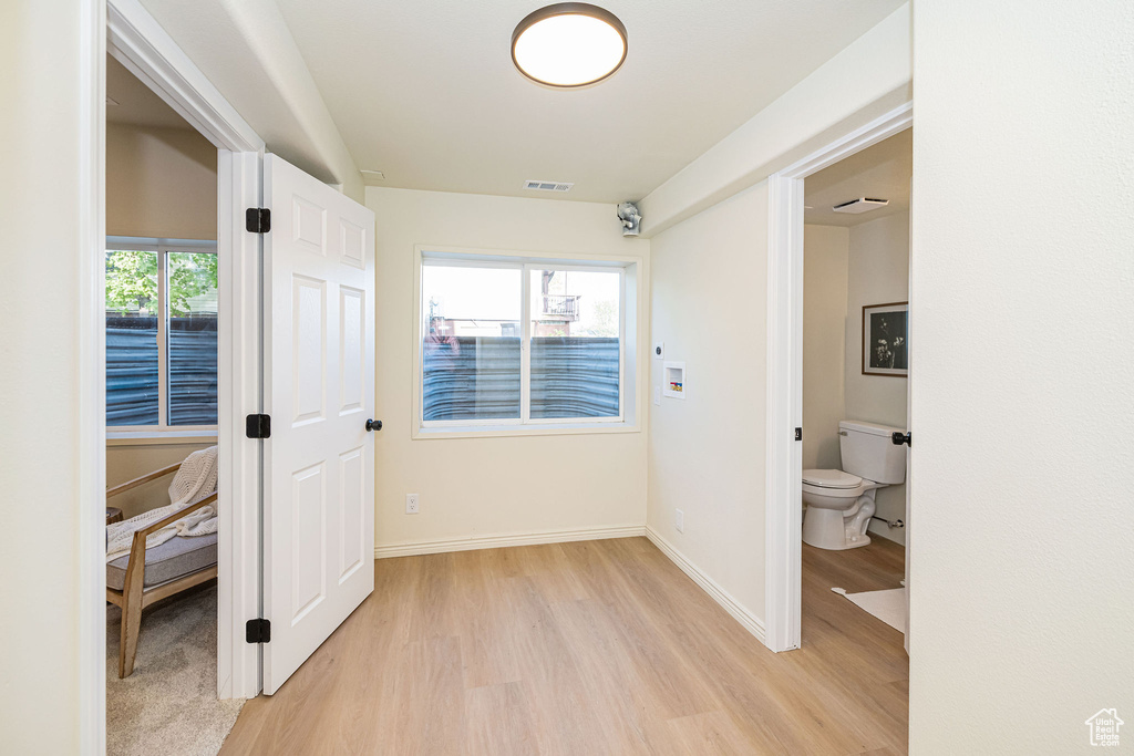 Hall with baseboards, light wood-style flooring, and visible vents