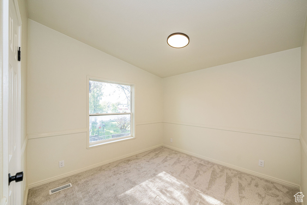 Unfurnished room featuring visible vents, carpet flooring, baseboards, and lofted ceiling