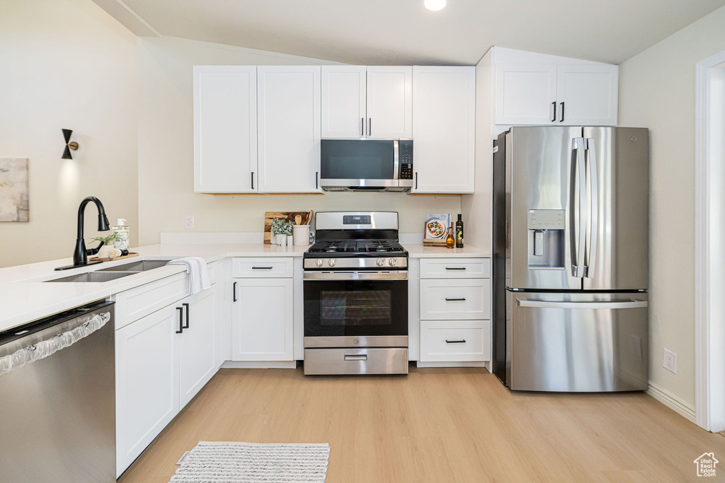 Kitchen featuring light wood-style floors, a sink, white cabinetry, and appliances with stainless steel finishes