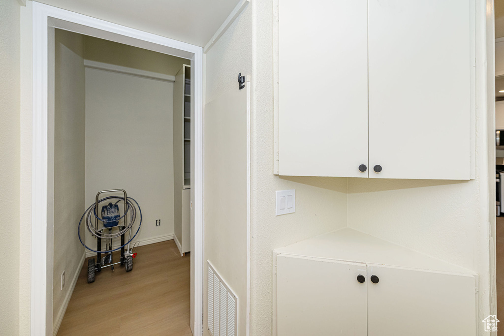Hallway with baseboards, light wood-style flooring, and visible vents