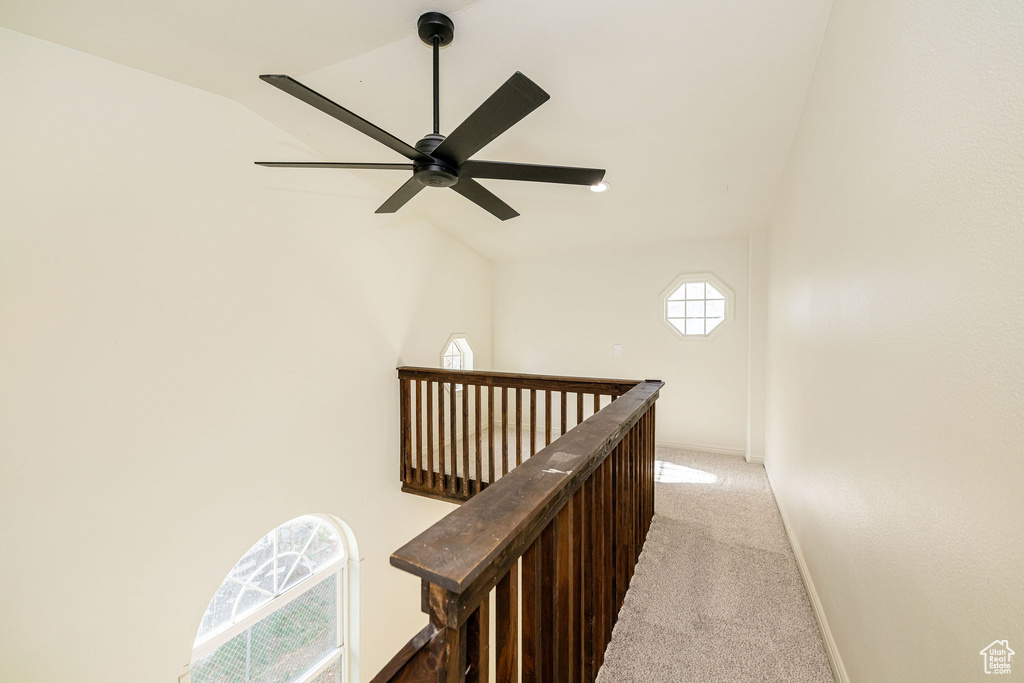 Corridor with light colored carpet, an upstairs landing, and lofted ceiling