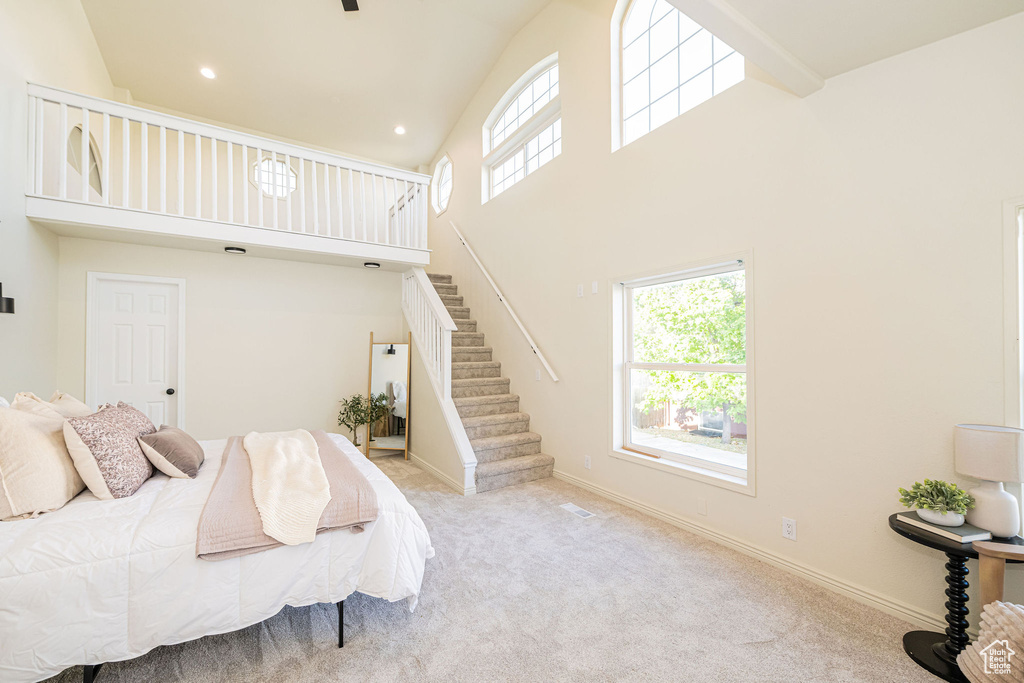 Bedroom with high vaulted ceiling, multiple windows, and carpet flooring
