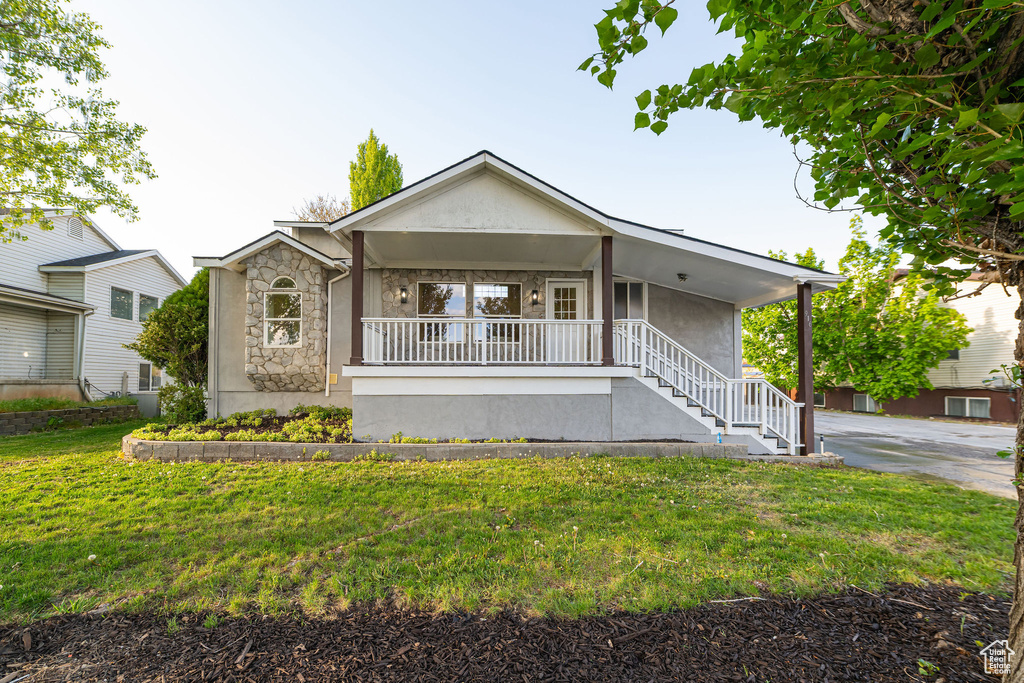 Ranch-style home featuring a front lawn, stone siding, stucco siding, a porch, and stairway