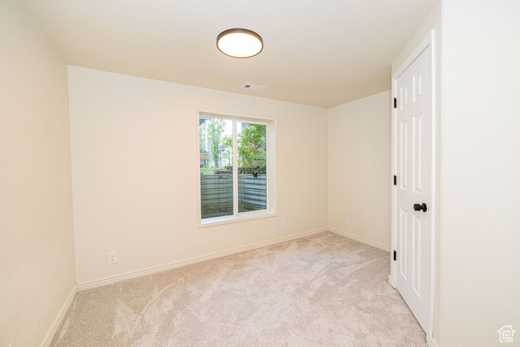 Carpeted empty room with visible vents and baseboards