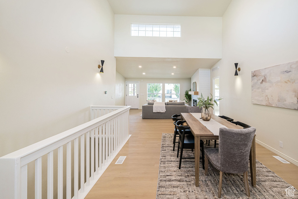Dining space featuring visible vents, light wood-style flooring, a towering ceiling, and baseboards