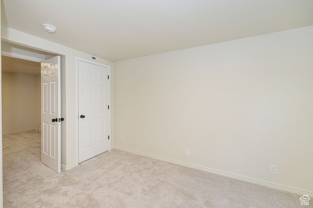 Unfurnished bedroom with baseboards and light colored carpet