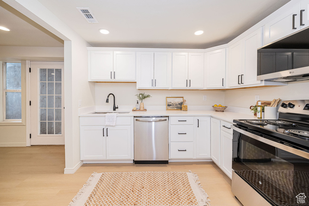 Kitchen featuring appliances with stainless steel finishes, a sink, light wood-style floors, light countertops, and visible vents