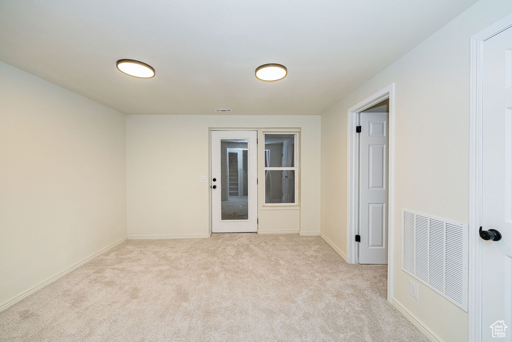 Unfurnished room featuring baseboards, visible vents, and light carpet